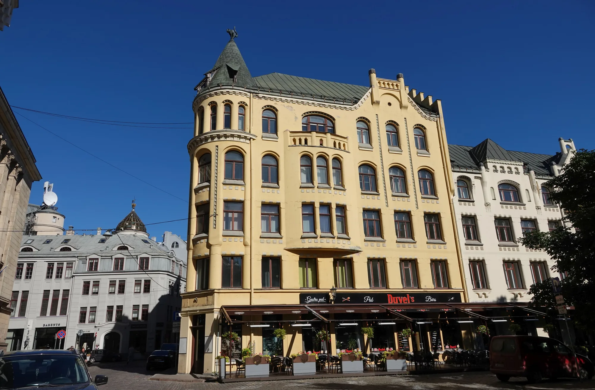 The yellow Art Nouveau Cat House in Riga, with a black cat sculpture perched atop its corner turret