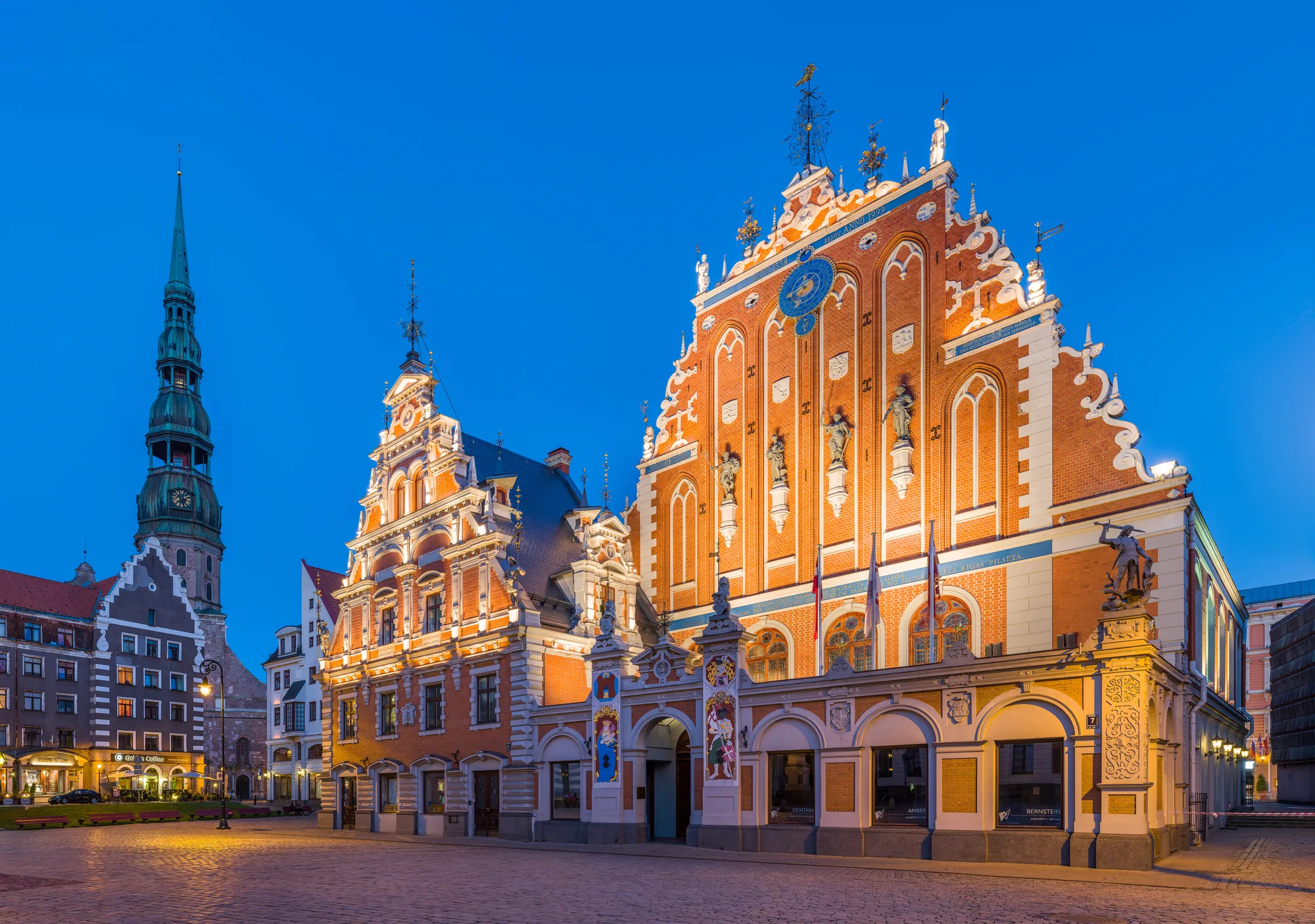 The ornate red Dutch-Renaissance gable of the House of the Blackheads on Town Hall Square in Riga, with St. Peter's spire behind