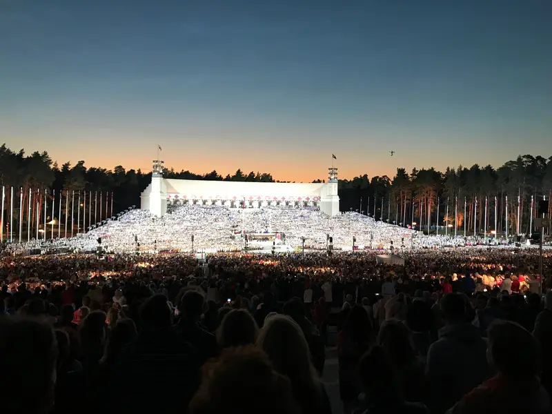 The white Great Bandstand in Mezaparks, Riga, ringed by pine forest during the Song Festival