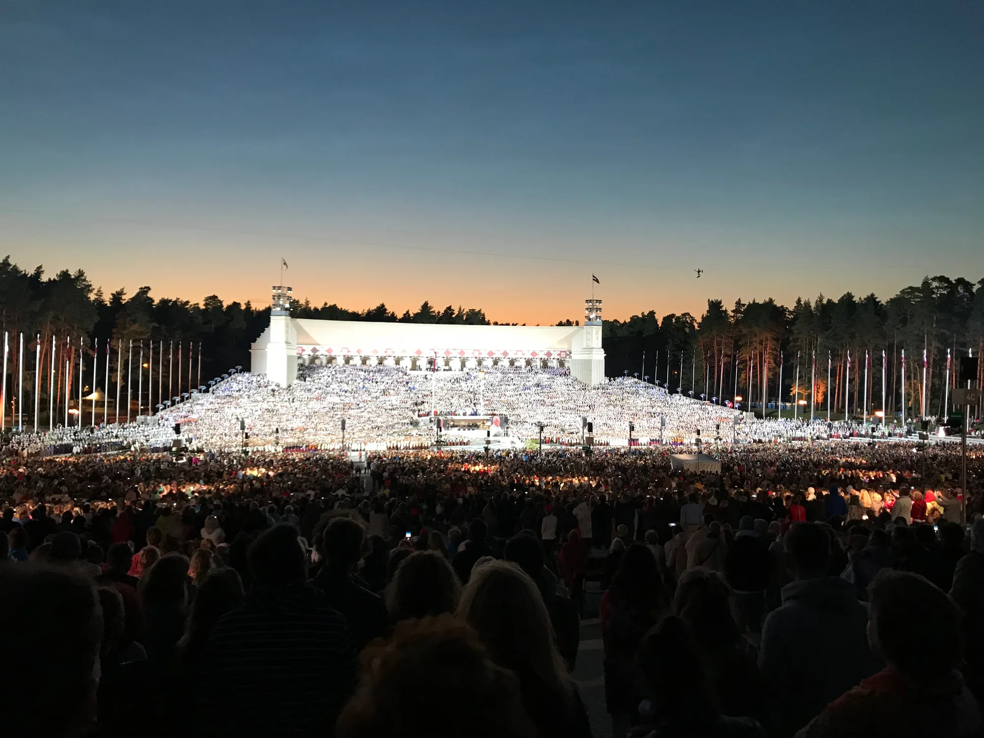 The white Great Bandstand in Mezaparks, Riga, ringed by pine forest during the Song Festival