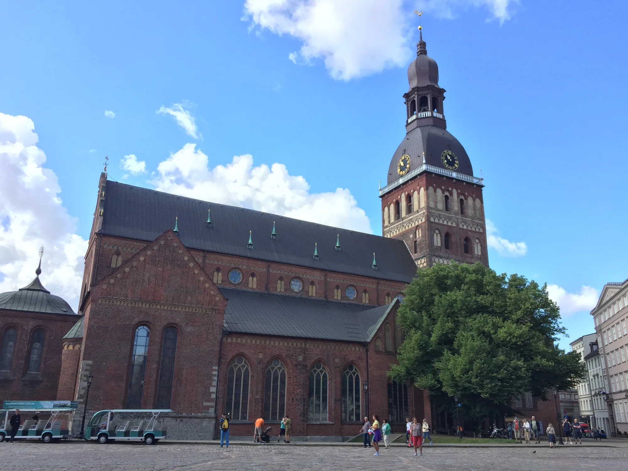 The red-brick Riga Cathedral (Rigas Doms) with its tall tower and dark cupola, seen across cobbled Dome Square