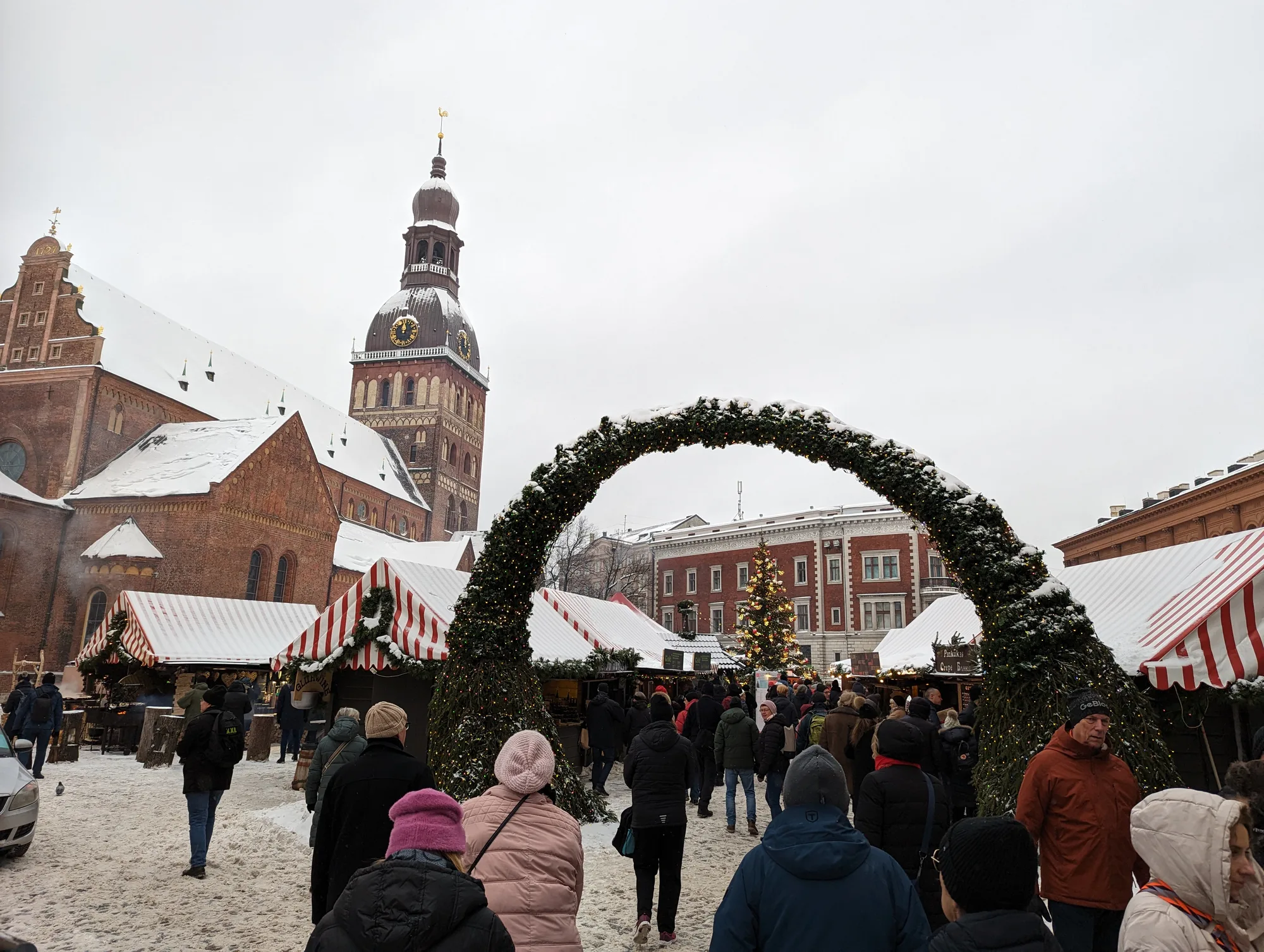 The Riga Christmas market on Dome Square, with red-and-white stalls and a decorated tree below the Cathedral tower
