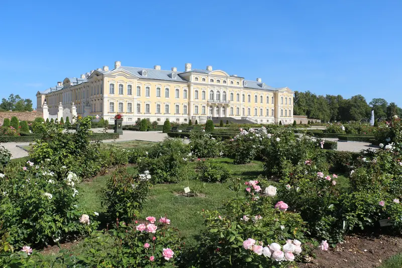 Rundale Palace, a grand yellow-and-white Baroque palace with a formal rose garden in the foreground