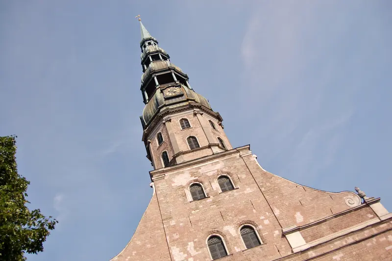 The tall brick tower of St. Peter's Church in Riga, with its distinctive dark tiered baroque spire and clock